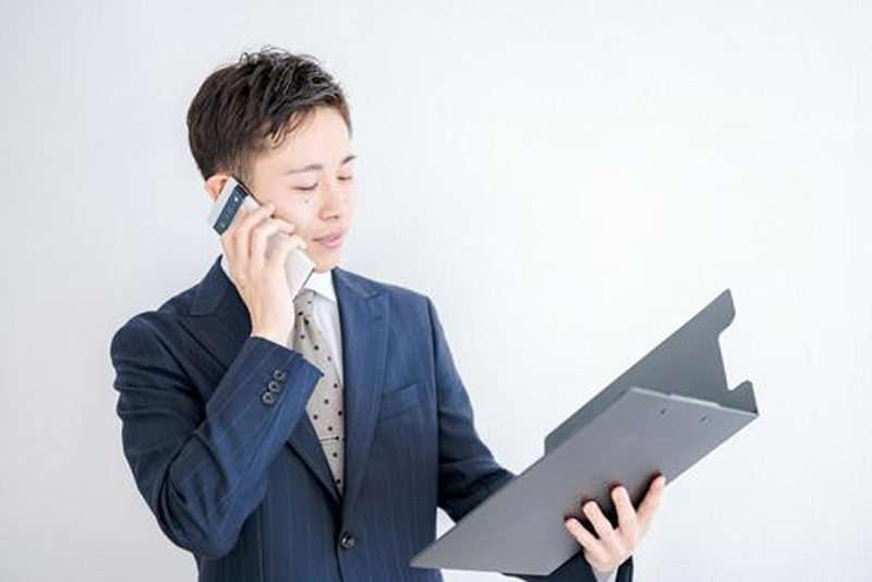 査定額をスマホ通話で伝えるスーツ男性